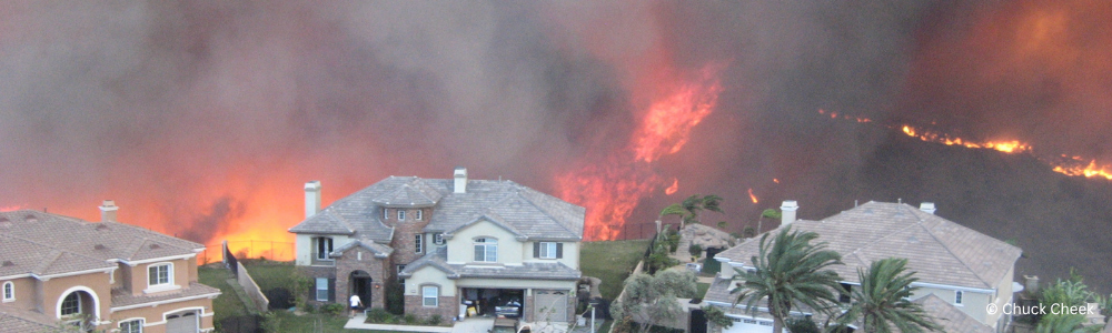 Homes in the foreground with wildfire burning a hillside behind it.